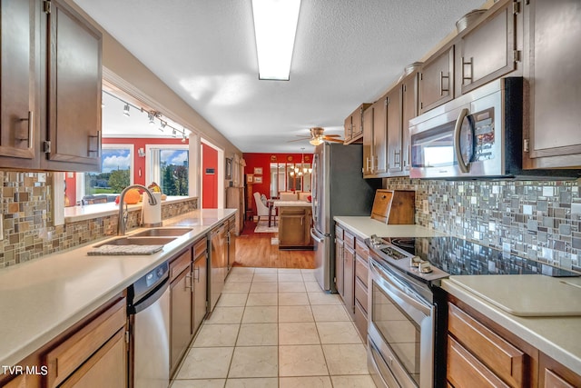 kitchen with ceiling fan, stainless steel appliances, tasteful backsplash, sink, and light tile patterned floors