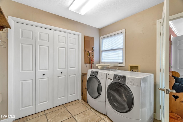 laundry area with washing machine and clothes dryer, light tile patterned floors, and a textured ceiling