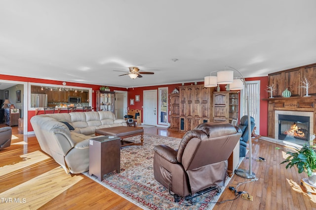 living room with ceiling fan, light hardwood / wood-style floors, crown molding, and a tile fireplace