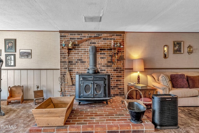 living room with brick wall, a textured ceiling, wood walls, and a wood stove