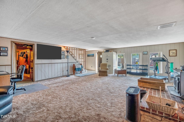 living room featuring carpet flooring, wooden walls, and a textured ceiling