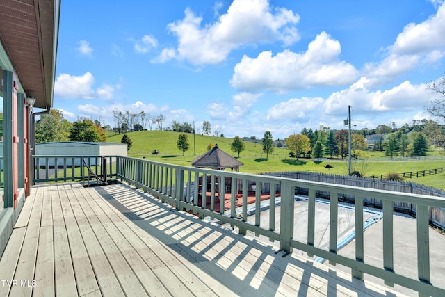 deck featuring a rural view, a swimming pool, and a yard