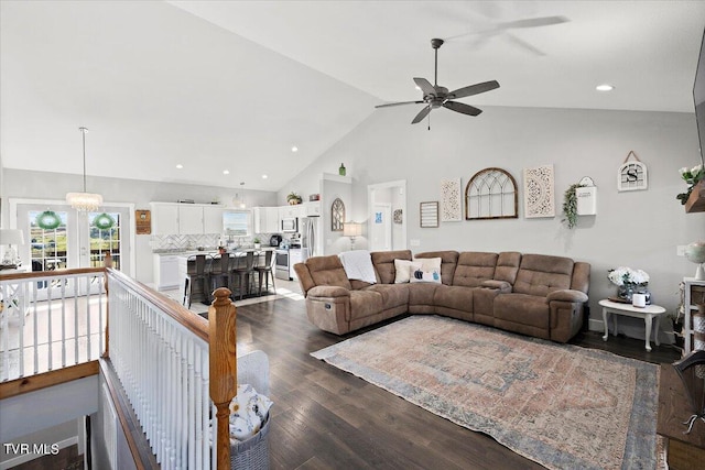 living room with ceiling fan with notable chandelier, high vaulted ceiling, and dark hardwood / wood-style flooring