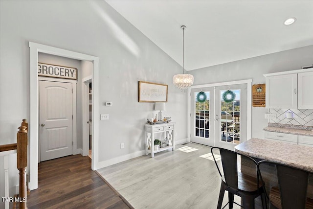 dining space with french doors, a chandelier, vaulted ceiling, and hardwood / wood-style flooring