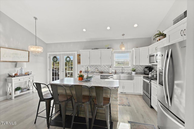 kitchen with lofted ceiling, plenty of natural light, stainless steel appliances, and a center island