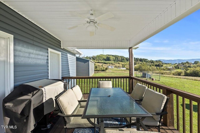 wooden terrace featuring a yard, ceiling fan, and a grill