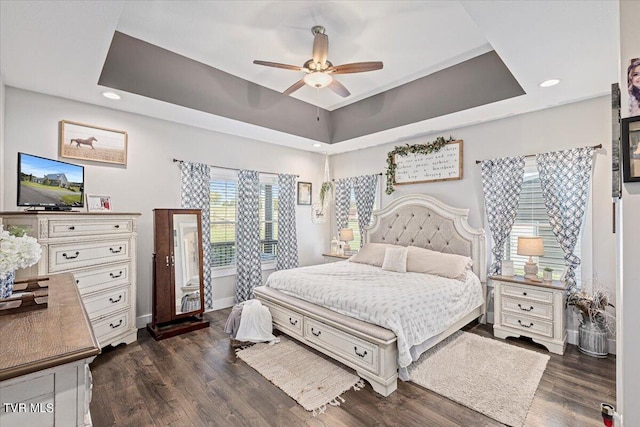 bedroom with ceiling fan, a tray ceiling, and dark hardwood / wood-style floors