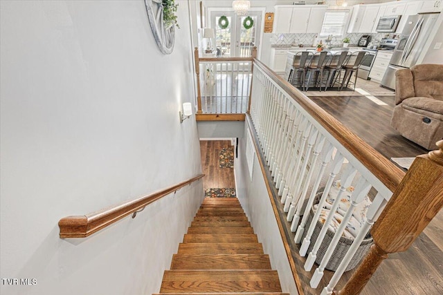 stairs featuring a notable chandelier and wood-type flooring