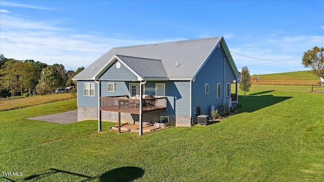 back of property with a deck, central AC unit, a lawn, and a patio area