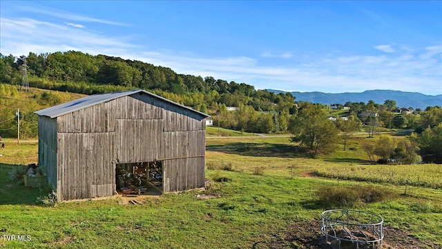 view of outdoor structure featuring a mountain view, a rural view, and a lawn