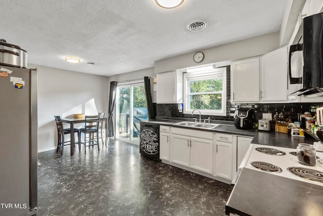 kitchen with stainless steel refrigerator, sink, decorative backsplash, white cabinets, and a textured ceiling