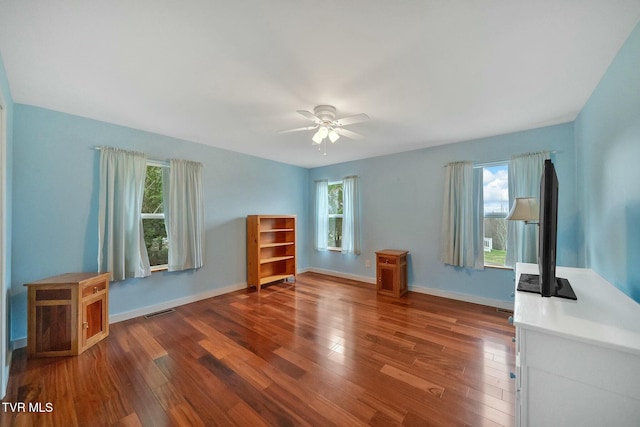 interior space with multiple windows, ceiling fan, and dark hardwood / wood-style flooring