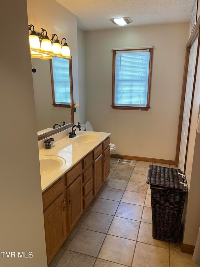 bathroom with a wealth of natural light, toilet, vanity, and a textured ceiling