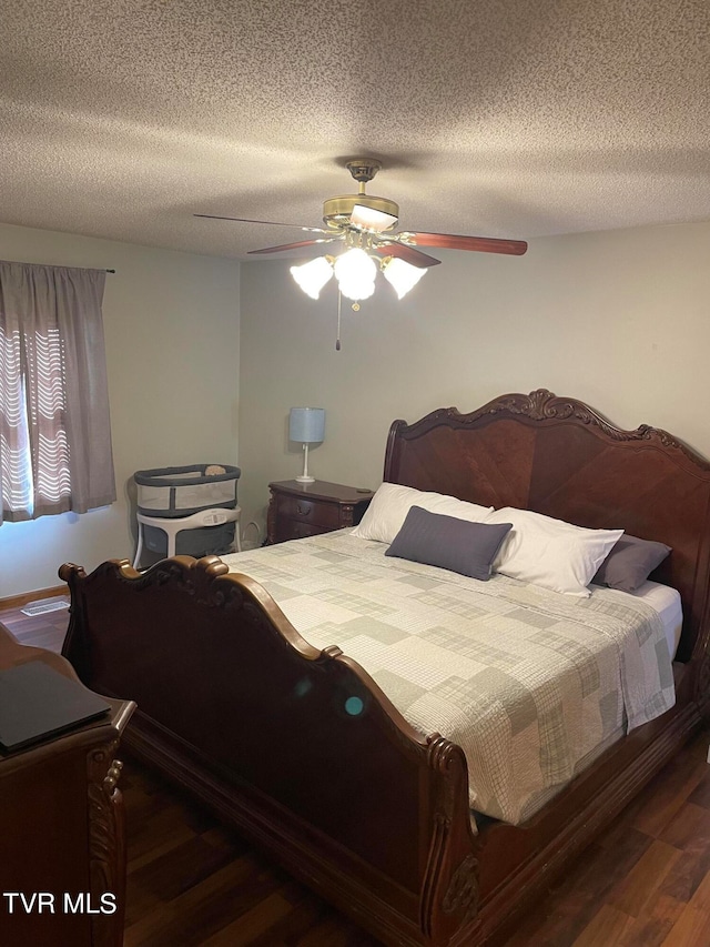 bedroom with ceiling fan, a textured ceiling, and dark hardwood / wood-style floors