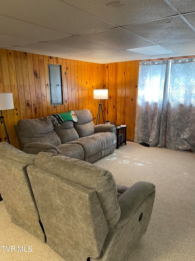 carpeted living room featuring electric panel, a drop ceiling, and wooden walls