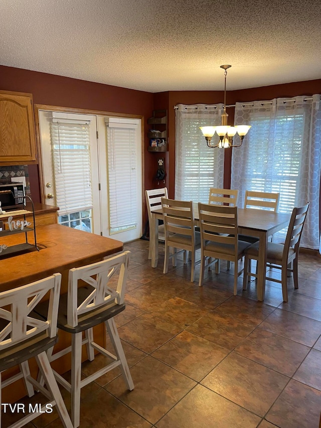 dining room with dark tile patterned flooring, a textured ceiling, and a chandelier