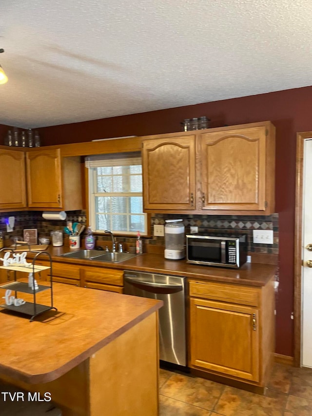 kitchen featuring tasteful backsplash, appliances with stainless steel finishes, sink, and a textured ceiling