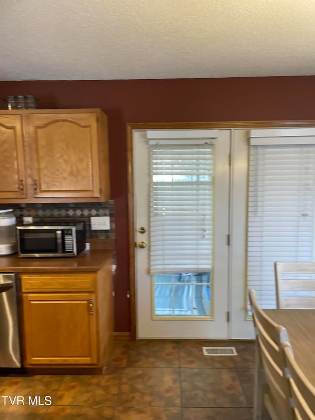 kitchen with appliances with stainless steel finishes and dark tile patterned floors