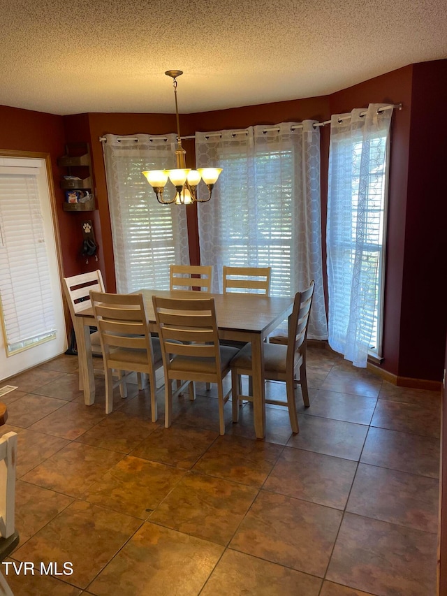 tiled dining room featuring a chandelier and a textured ceiling