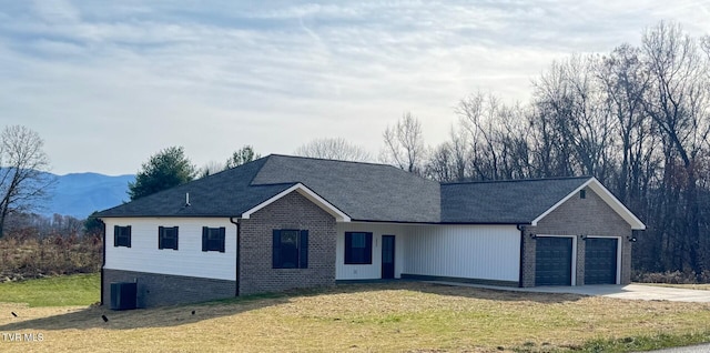 ranch-style house featuring a garage, a front lawn, and cooling unit