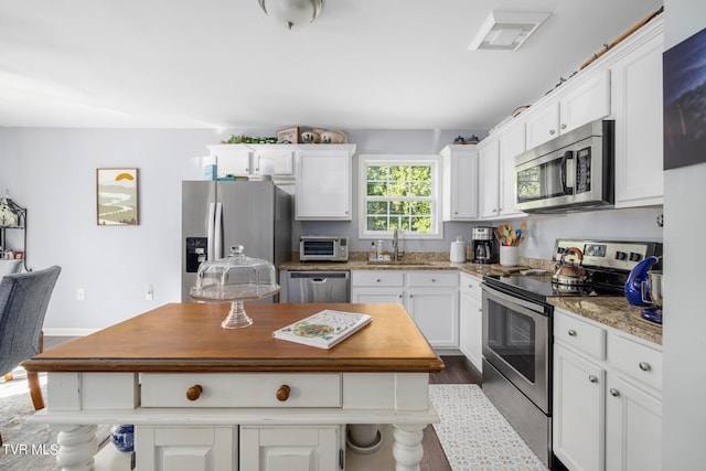 kitchen featuring sink, stainless steel appliances, light stone countertops, dark hardwood / wood-style floors, and white cabinets