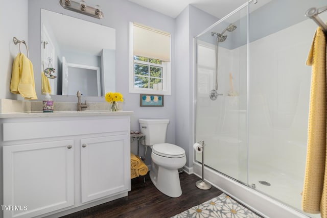 bathroom featuring wood-type flooring, vanity, a shower with shower door, and toilet