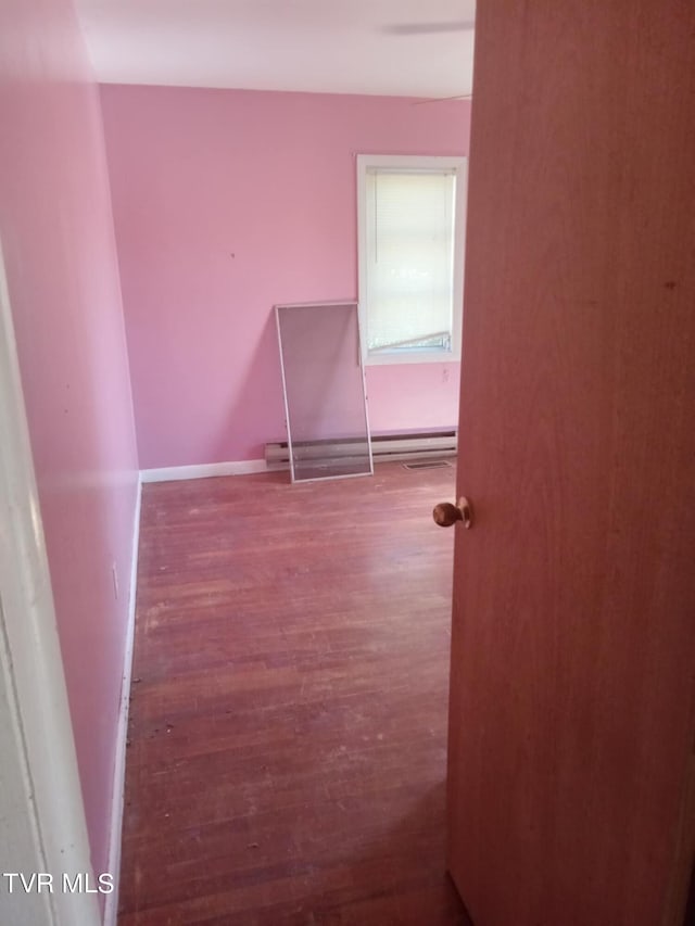 spare room featuring a baseboard radiator and hardwood / wood-style floors