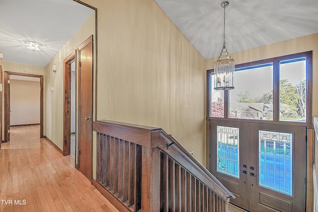 entrance foyer with french doors, an inviting chandelier, and light wood-type flooring