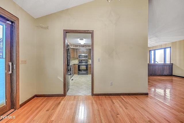 foyer with a textured ceiling, light hardwood / wood-style floors, and lofted ceiling