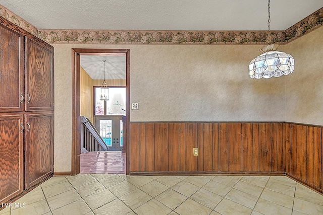 foyer with wooden walls, a textured ceiling, and a notable chandelier