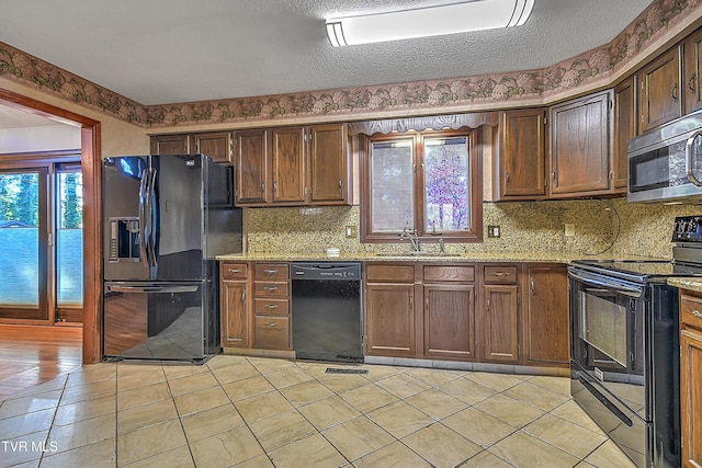 kitchen with light stone countertops, sink, a textured ceiling, decorative backsplash, and black appliances