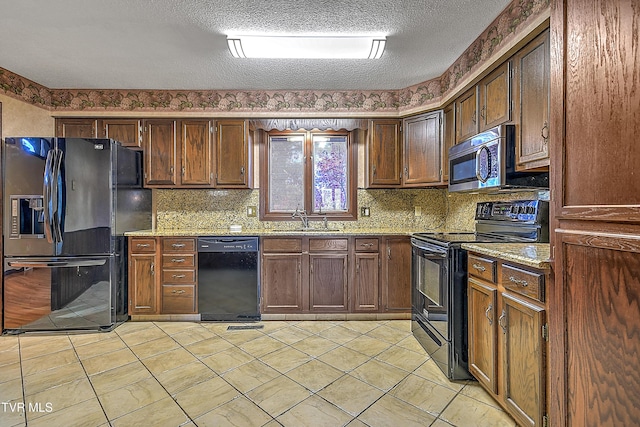 kitchen featuring black appliances, sink, light stone countertops, and a textured ceiling