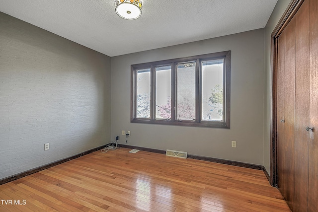 spare room featuring a textured ceiling and light wood-type flooring