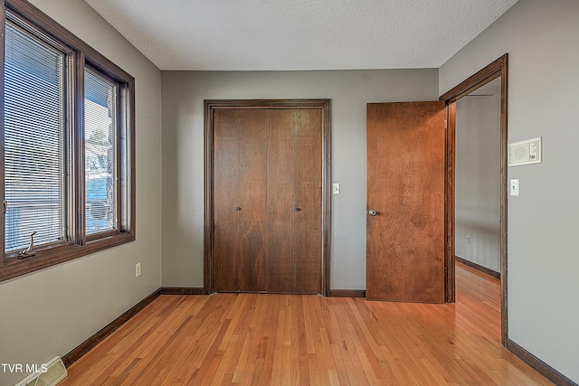 unfurnished bedroom featuring a textured ceiling and light hardwood / wood-style flooring