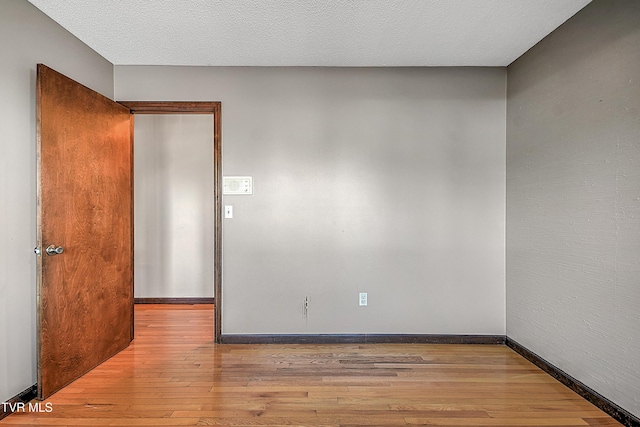 empty room featuring a textured ceiling and light hardwood / wood-style floors