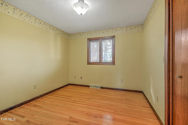 empty room featuring a textured ceiling and light hardwood / wood-style floors