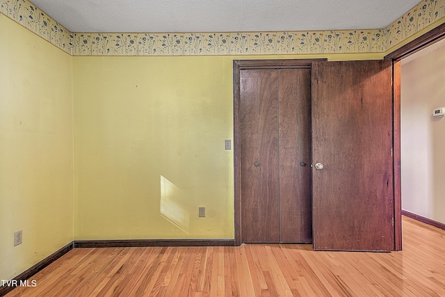 unfurnished bedroom with a textured ceiling and light wood-type flooring