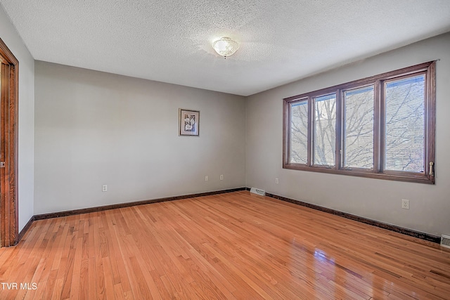 empty room featuring light hardwood / wood-style flooring and a textured ceiling