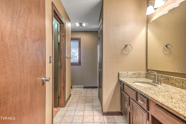 bathroom with tile patterned floors, vanity, and a textured ceiling