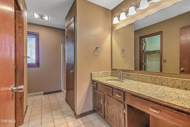 bathroom featuring tile patterned flooring, vanity, a shower with door, and a textured ceiling