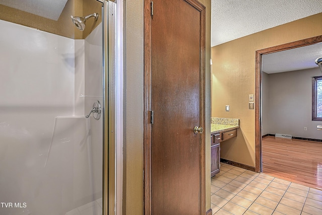 bathroom featuring a shower, hardwood / wood-style floors, vanity, and a textured ceiling