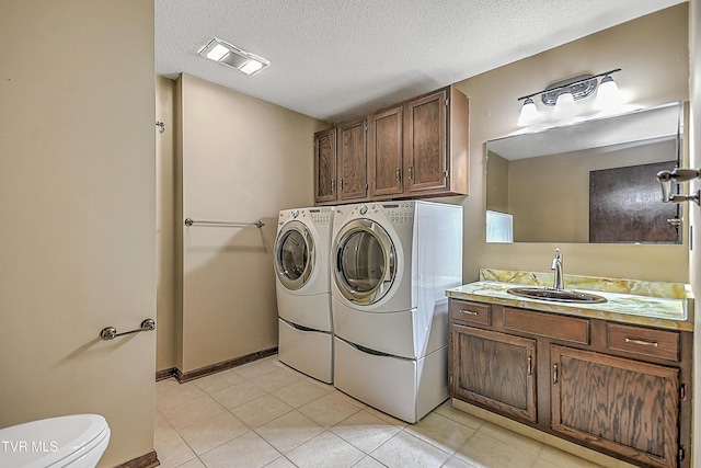 washroom with a textured ceiling, light tile patterned flooring, sink, and washing machine and clothes dryer