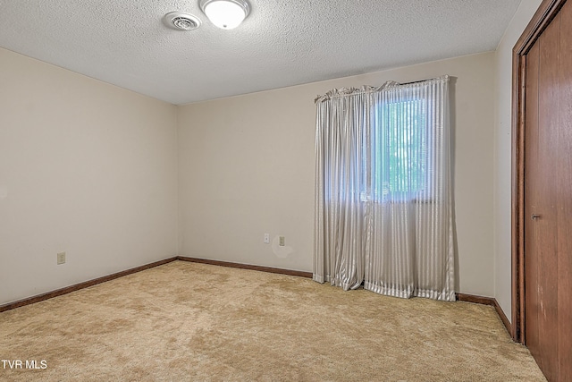 carpeted empty room with a textured ceiling