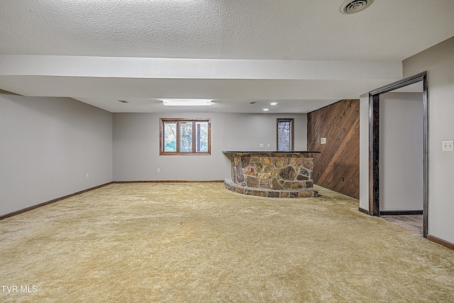 basement featuring wood walls, carpet floors, and a textured ceiling