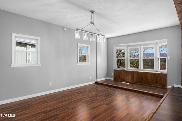 spare room with dark hardwood / wood-style flooring and an inviting chandelier