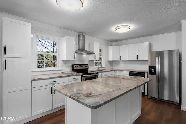 kitchen featuring wall chimney range hood, appliances with stainless steel finishes, white cabinetry, dark wood-type flooring, and a center island