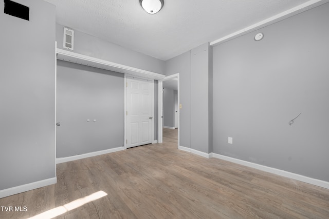 unfurnished bedroom featuring light hardwood / wood-style floors, a closet, and a textured ceiling