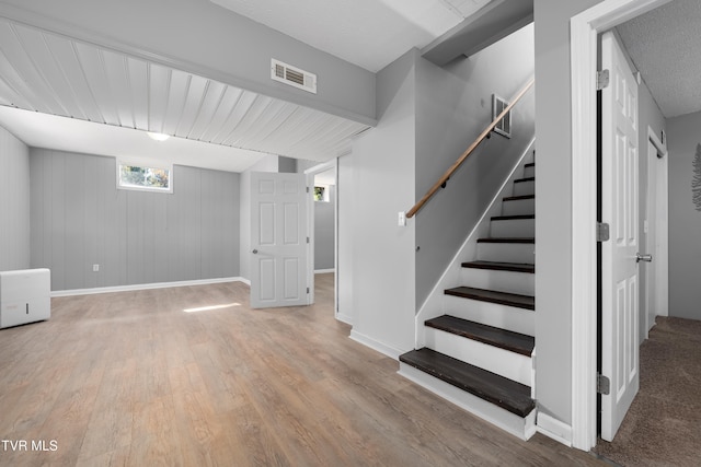 basement with wooden walls and light wood-type flooring