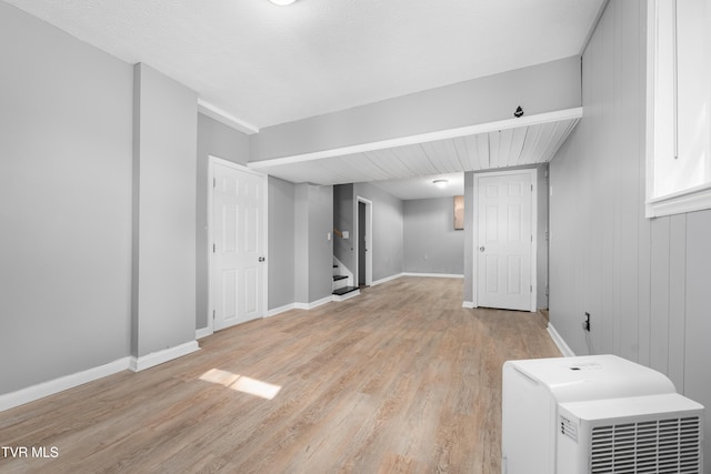 basement with wood walls, a textured ceiling, and light hardwood / wood-style flooring