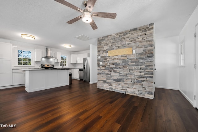 kitchen with wall chimney range hood, white cabinets, stainless steel fridge, a textured ceiling, and dark wood-type flooring